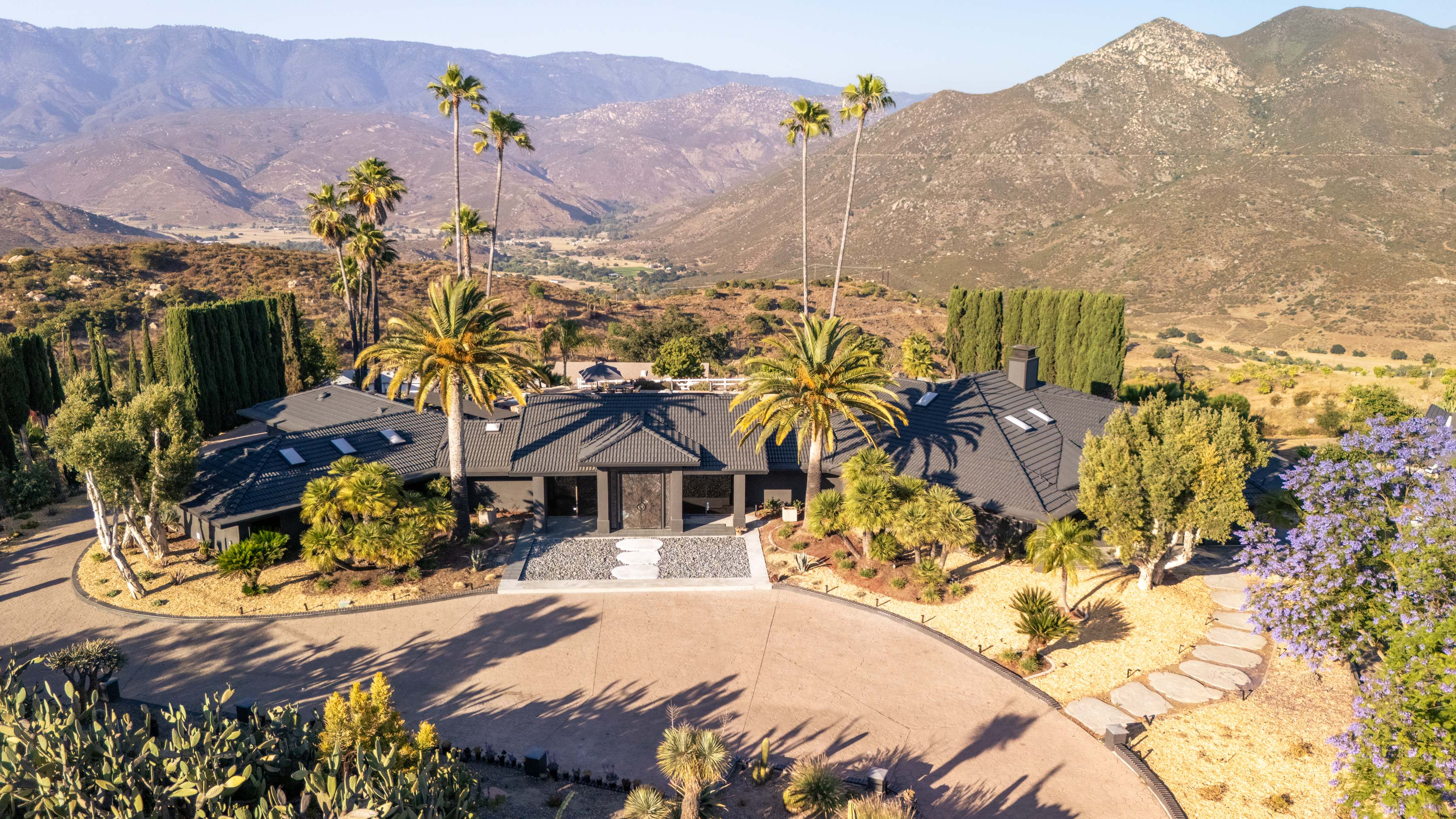 Casa Del Sol aerial view - front entrance with circular driveway and mountain backdrop