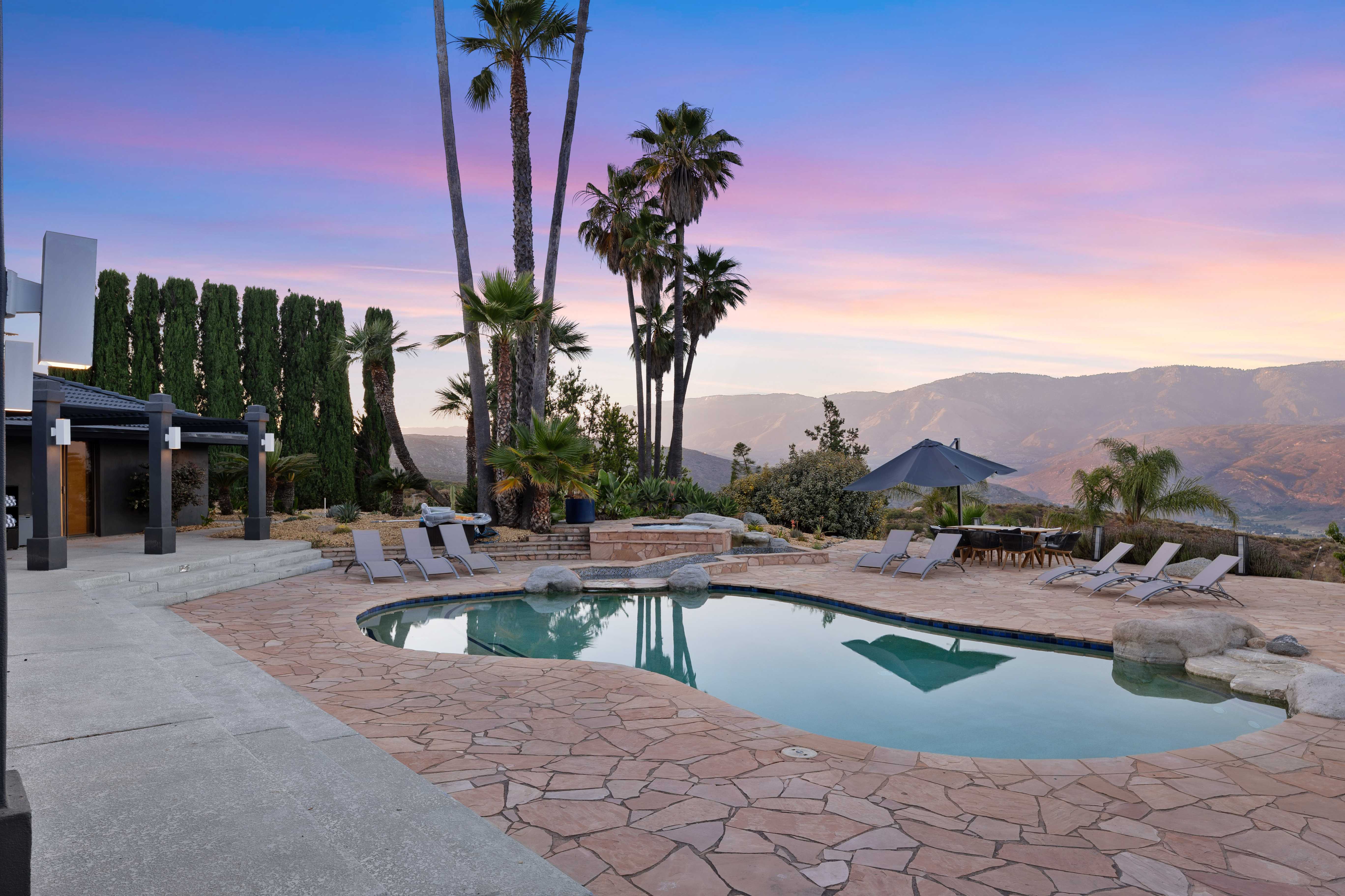 Pool and patio at sunset with palm trees and mountain views