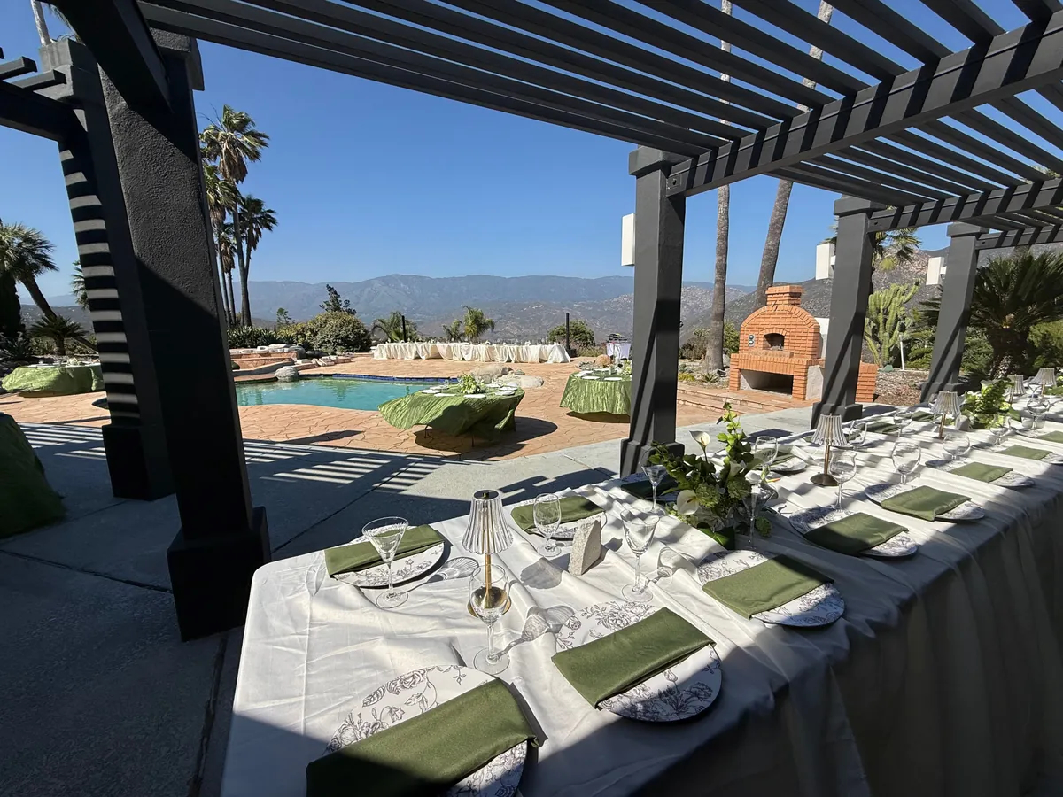 Outdoor dining setup under pergola overlooking pool and mountains